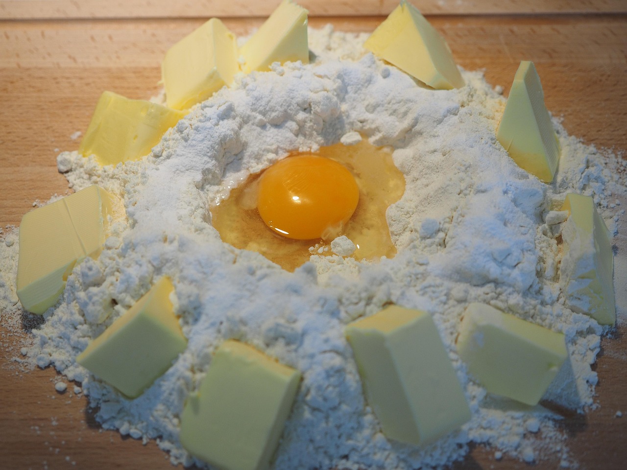 Eggs, flour, butter, and baking tools arranged on a wooden work surface